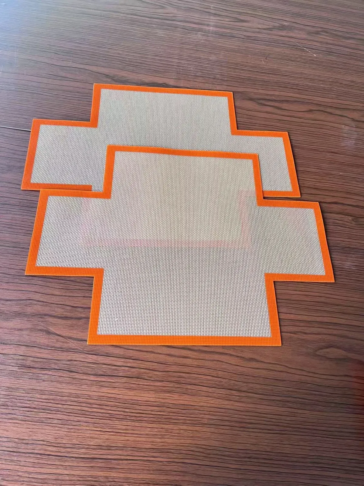 Orange-bordered cross-shaped silicone fiberglass liners on a tabletop